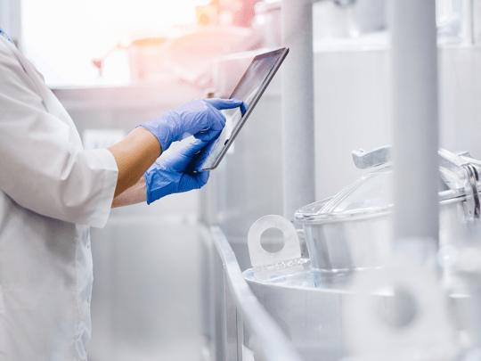 Concept food industry banner. Factory worker inspecting production line tanker in of dairy factory with computer tablet